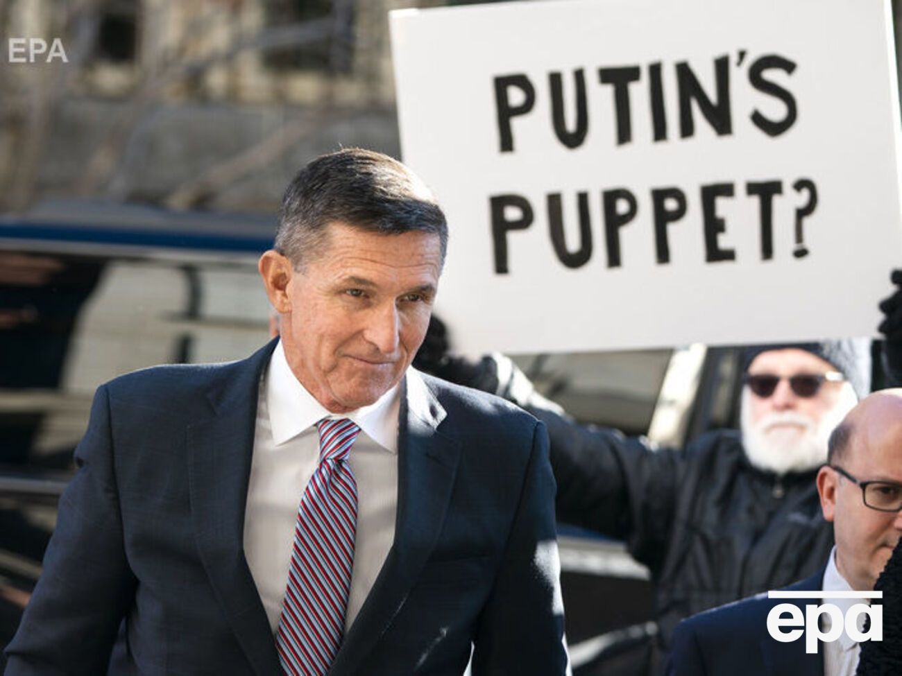 Флінн біля будівлі суду у Вашингтоні 2018 року; напис на плакаті "Путінська маріонетка"