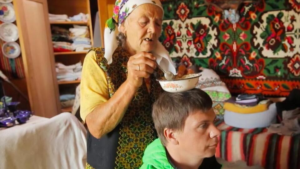 Український телеведучий Дмитро Комаров слухає пророцтва карпатської мольфарки Марії Цвілинів