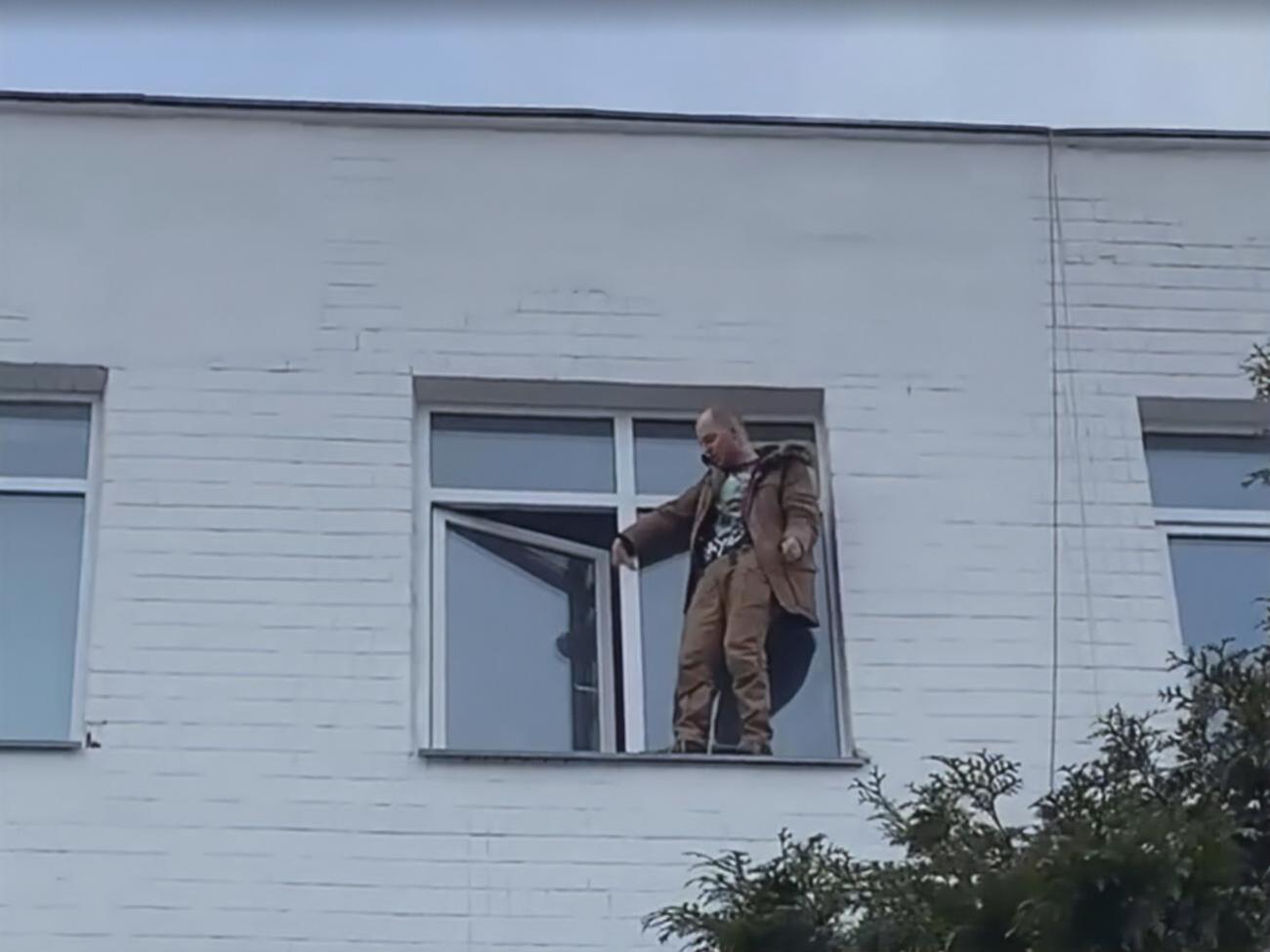 Мужчина стоял на внешней стороне подоконника на четвертом этаже здания