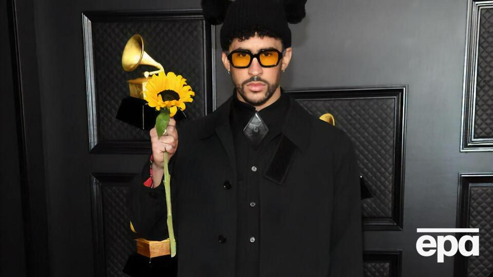 Bad Bunny посетил "Грэмми 2021" в черном пальто, плиссированном платье и высоких ботинках на шнуровке, дополнив образ шапкой с ушами