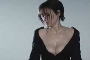 Райдер позирует в кадре в черном платье с глубоким декольте