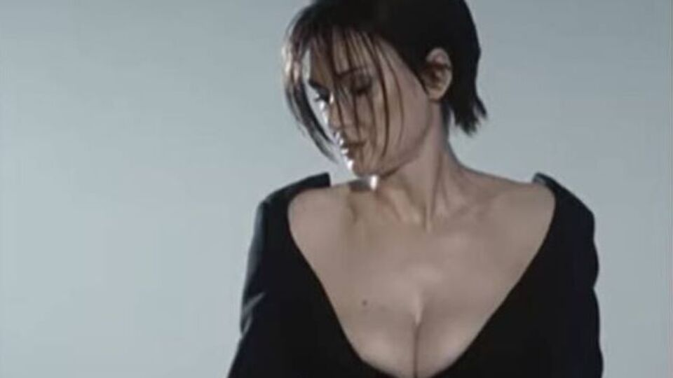 Райдер позирует в кадре в черном платье с глубоким декольте