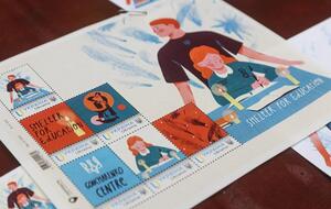 На марке изображен собирательный образ учителя, защищающего ученицу, пока за его спиной разрываются снаряды