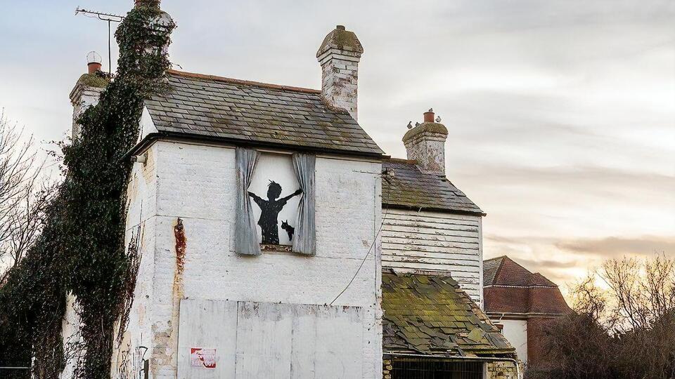 Бэнкси изобразил на заколоченном фанерой окне дома мальчика с разведенными руками, который якобы раздвигает занавески из смятых листов металла