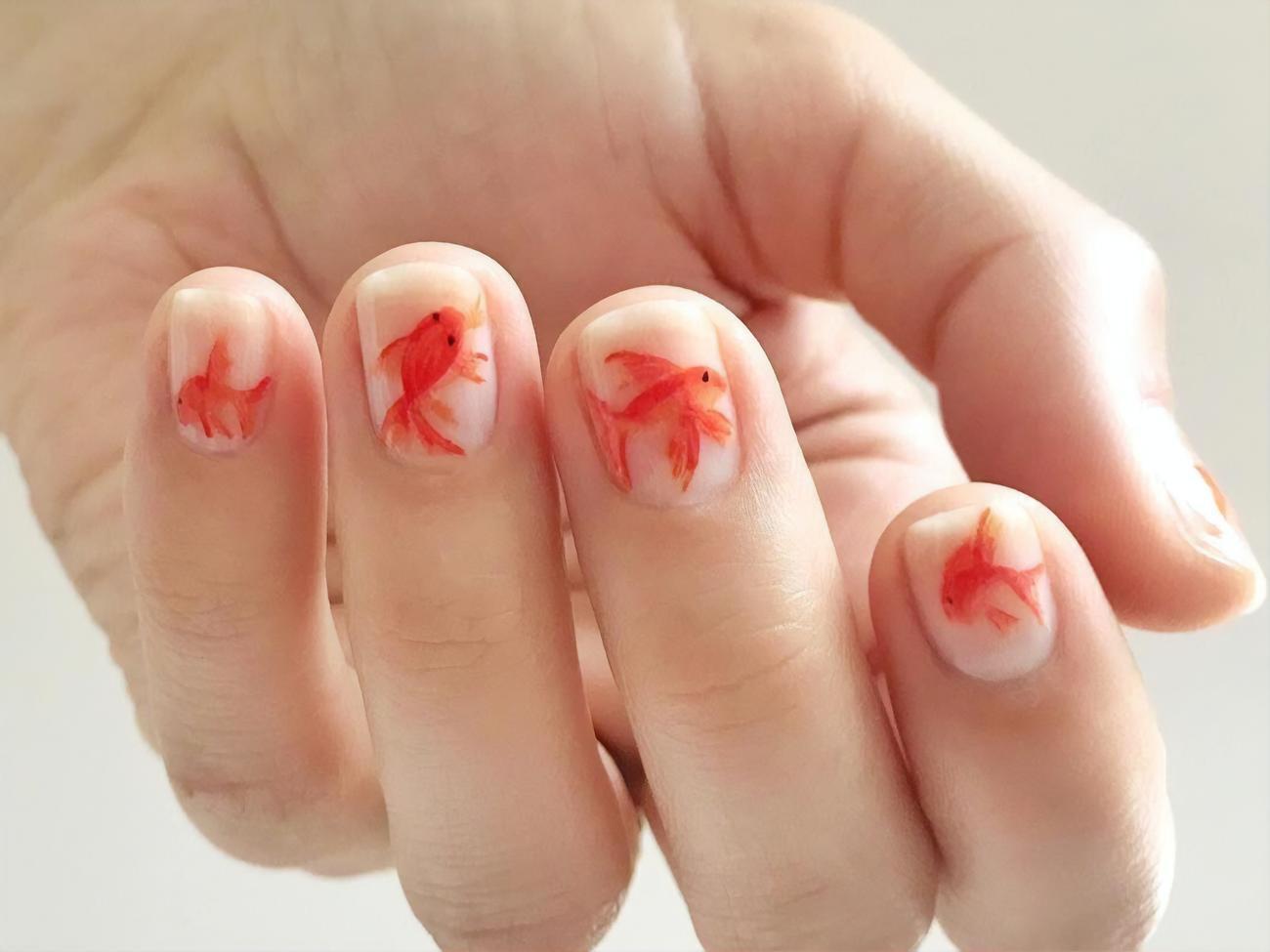 Маникюр с золотыми рыбками смотрится так, будто для него использовали акварельные краски