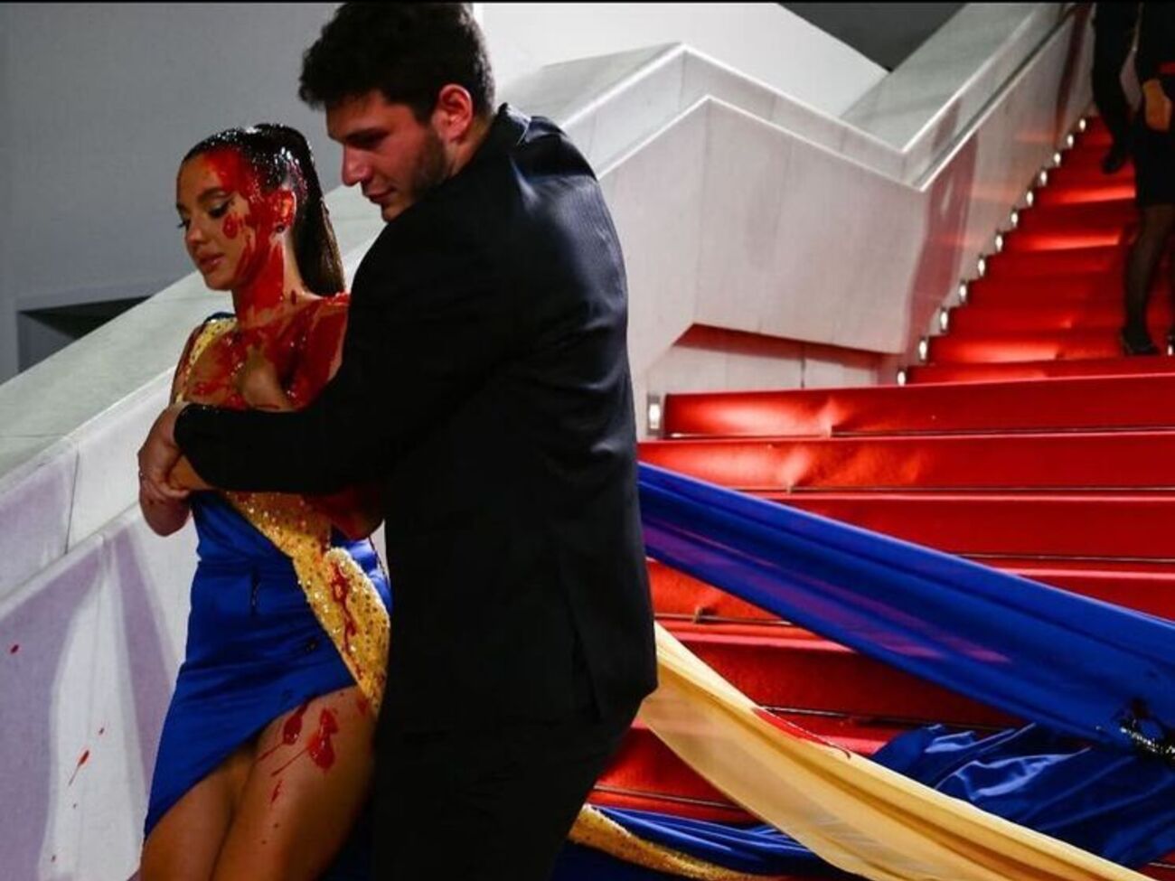 После того как активистка облилась краской, к ней подбежал человек в костюме и за руки потащил вниз по лестнице