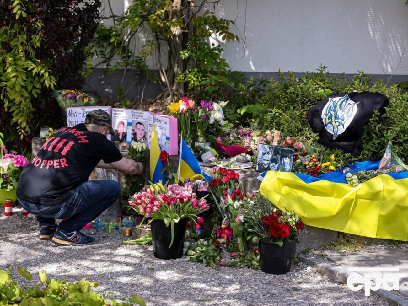 Люди несут цветы к месту убийства украинцев