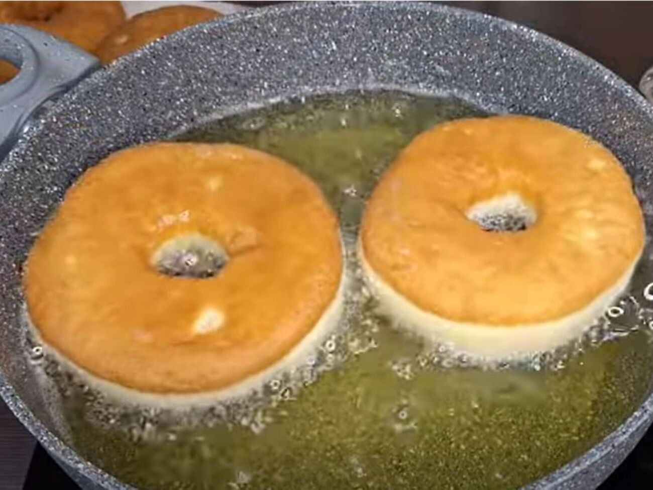 Разогрейте растительное масло на сковороде и обжарьте пончики с двух сторон