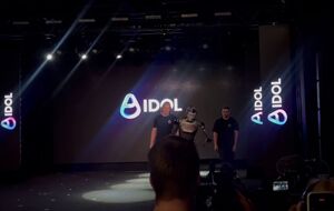 Aidol медленно вышел на сцену в сопровождении двух человек, но накренился и упал
