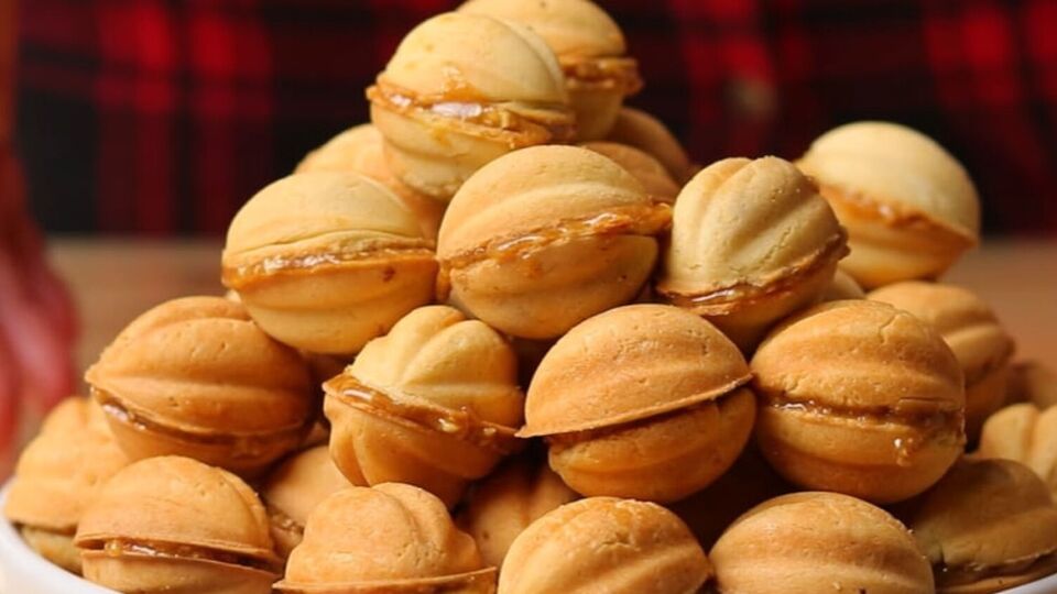 Начините половинки орехов карамелью и накройте второй частью, чтобы они склеились