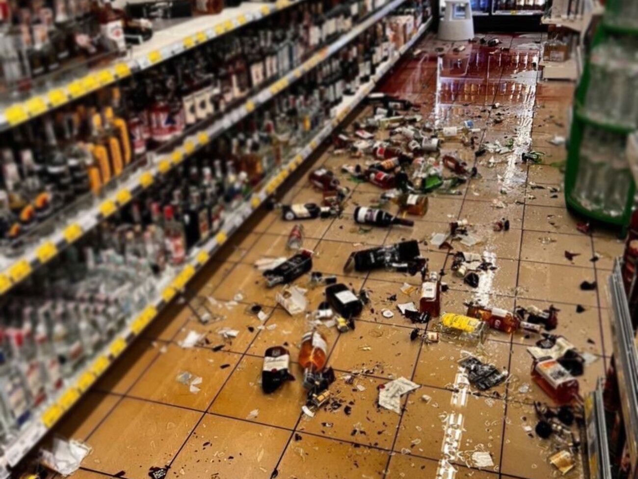 Чоловік брав пляшки з алкоголем з полиці в супермаркеті й кидав ними об землю