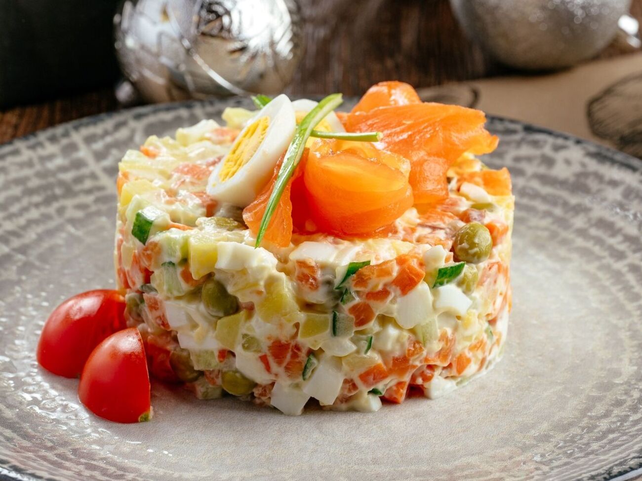 Из красной рыбы сделайте розочки и выложите их на салат. Присыпьте зеленым луком