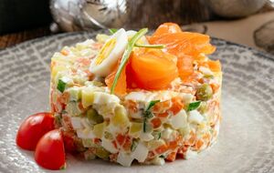 Из красной рыбы сделайте розочки и выложите их на салат. Присыпьте зеленым луком