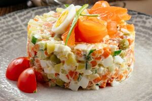 Из красной рыбы сделайте розочки и выложите их на салат. Присыпьте зеленым луком