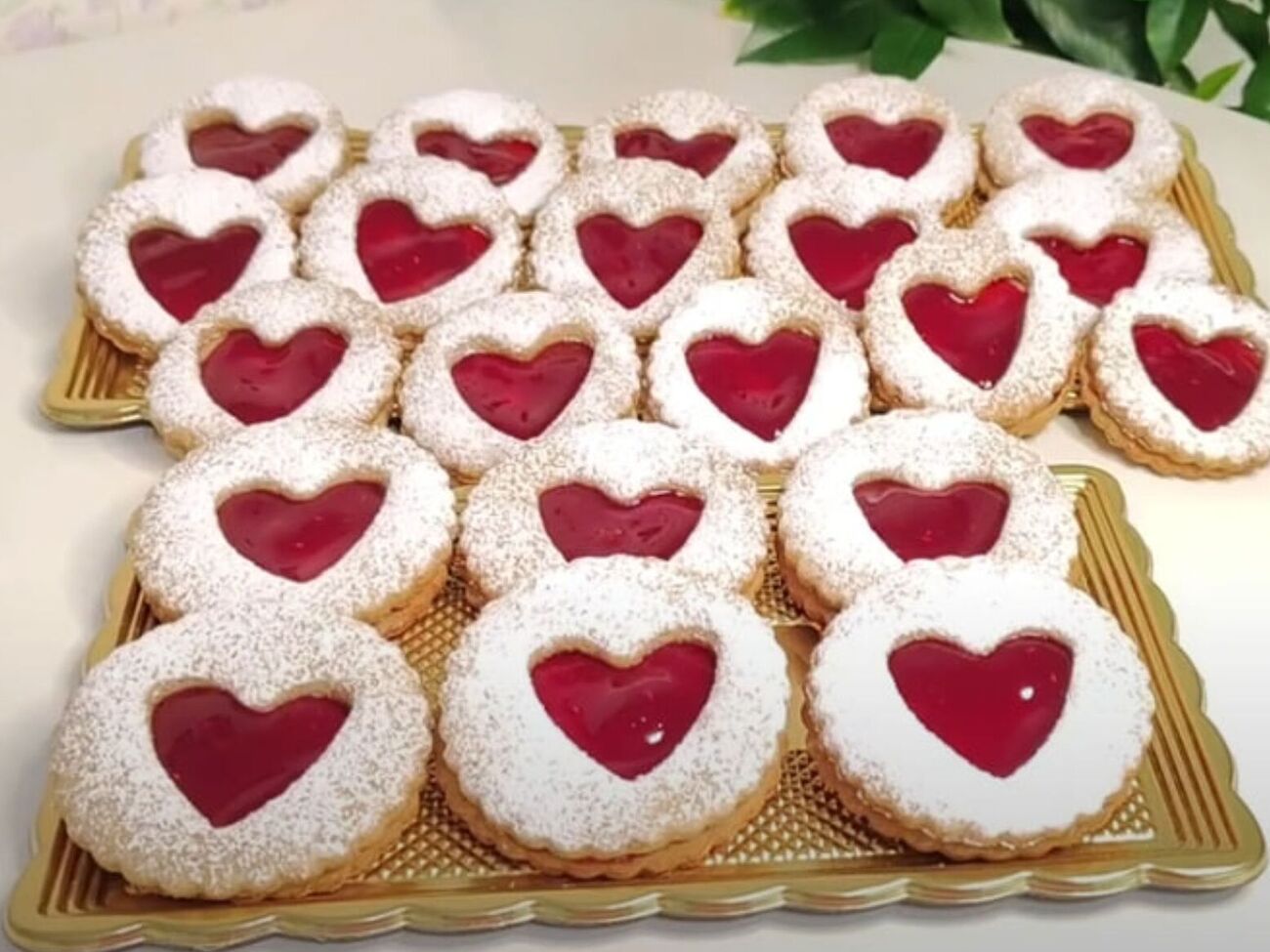 Целое печенье смажьте джемом и сверху на него выложите печенье с сердцами, посыпанное сахарной пудрой