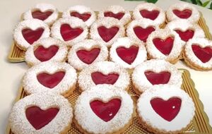 Целое печенье смажьте джемом и сверху на него выложите печенье с сердцами, посыпанное сахарной пудрой