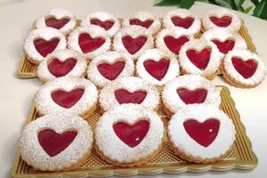 Целое печенье смажьте джемом и сверху на него выложите печенье с сердцами, посыпанное сахарной пудрой