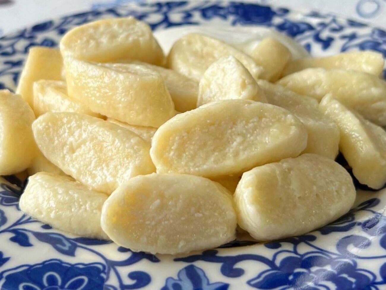 Выложите готовые вареники на тарелку и добавьте кусочек сливочного масла