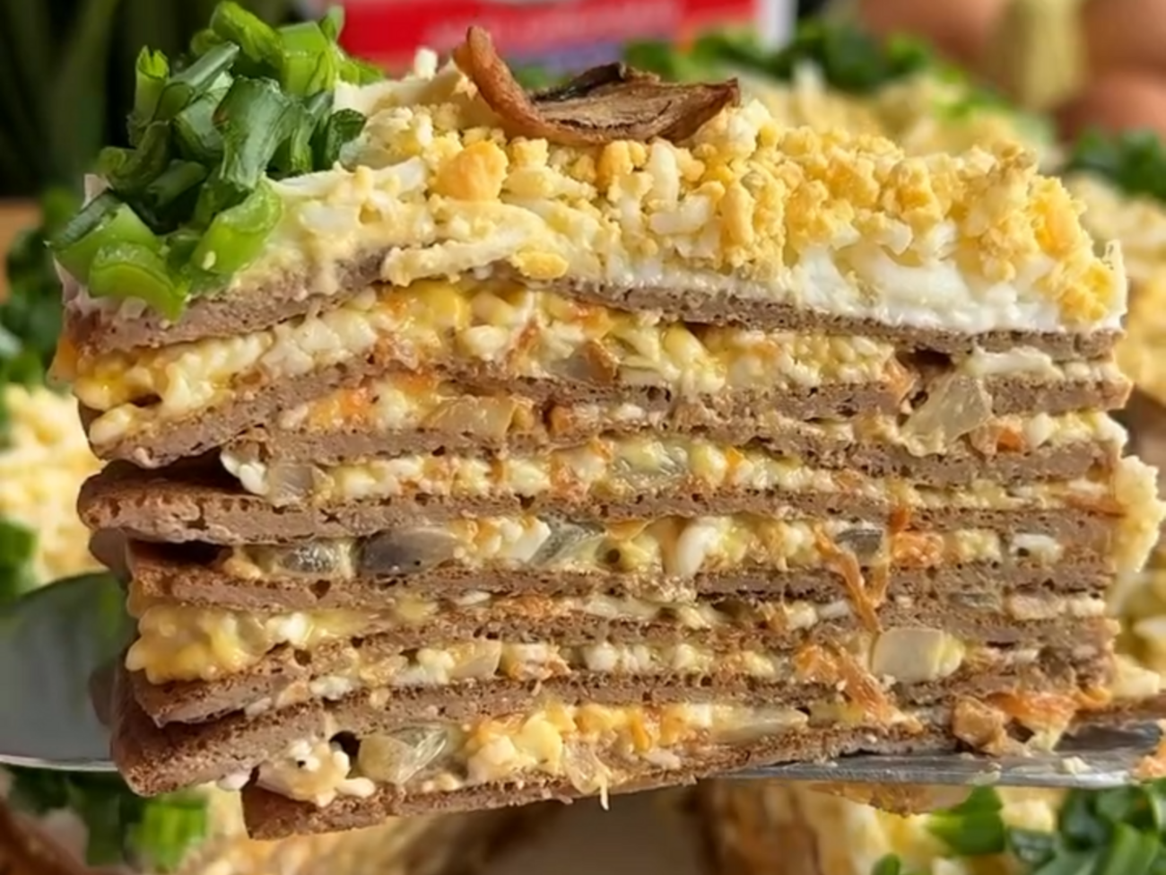 Верхний блин смажьте майонезом и посыпьте вареным яйцом, натертым на терку. Добавьте зелень и грибы