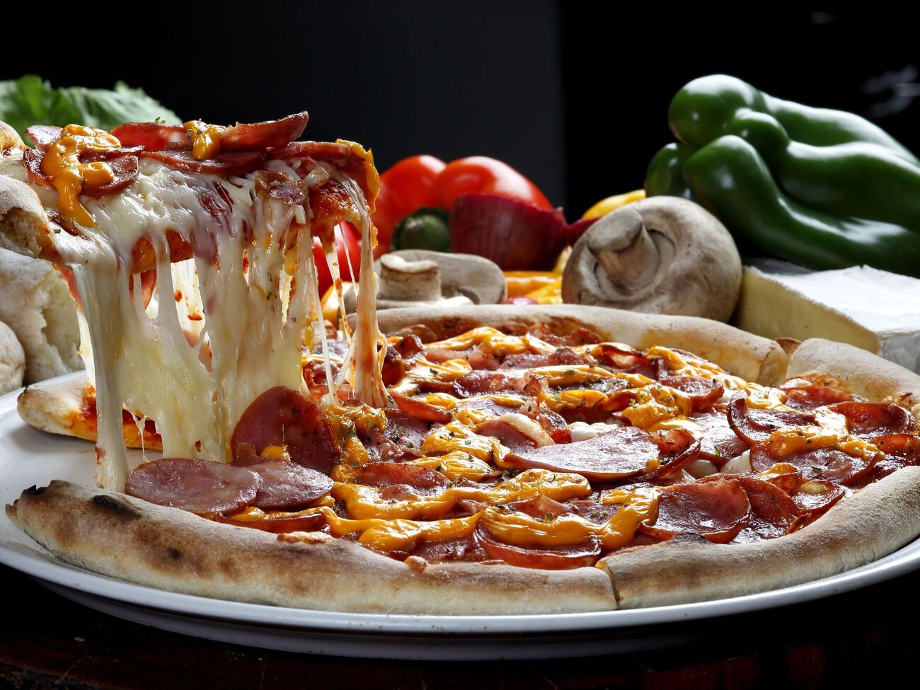 Основу для пиццы нужно поставить в разогретую до 220 °C духовку на пять минут, а затем уже выкладывать начинку