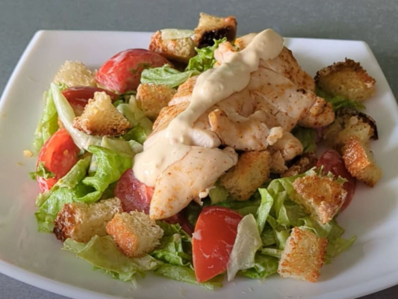 Для салата понадобятся филе курицы, листья салата, сухарики, томаты и соус