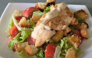 Для салата понадобятся филе курицы, листья салата, сухарики, томаты и соус