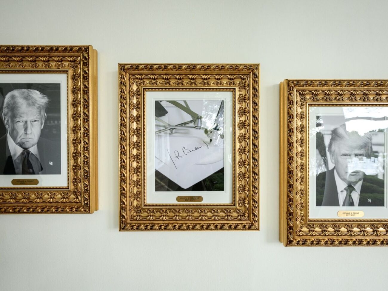 Фото автопена із підписом Байдена висить між двома портретами Трампа